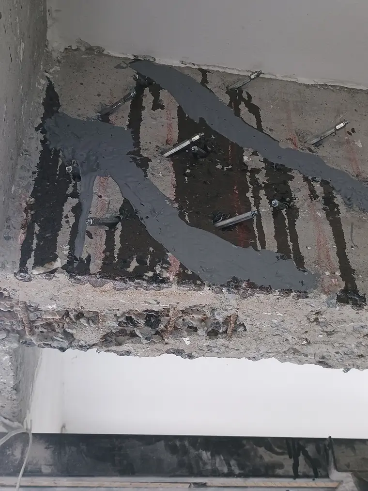 Estrutura de concreto com armadura exposta durante recuperação em subsolo de edifício.